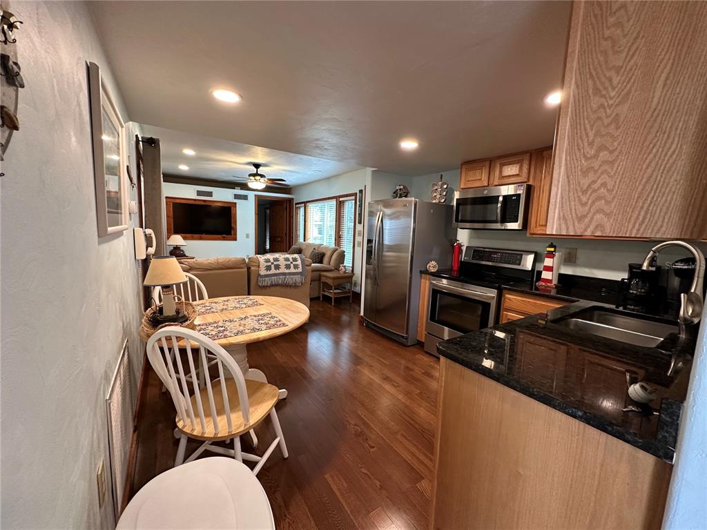 56315 Hickory Road Astor, FL 32102 - Photo 3 of 31 a kitchen with stainless steel appliances a stove a sink dishwasher a refrigerator and a dining table with wooden floor