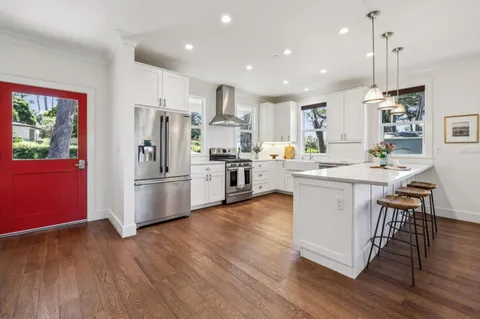 a large white kitchen with a large island oven a stove with wooden floors