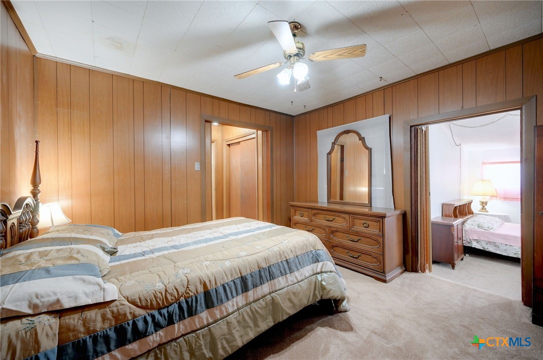1631 East Fannin Street Luling, TX 78648 - Photo 17 of 27 a bedroom with a large bed and a chandelier