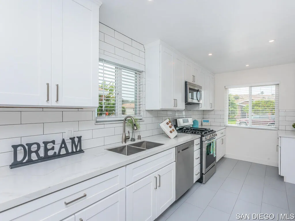 736 Snapdragon Street Encinitas, CA 92024 - Photo 4 of 25 a kitchen with a sink dishwasher stove and white cabinets with wooden floor