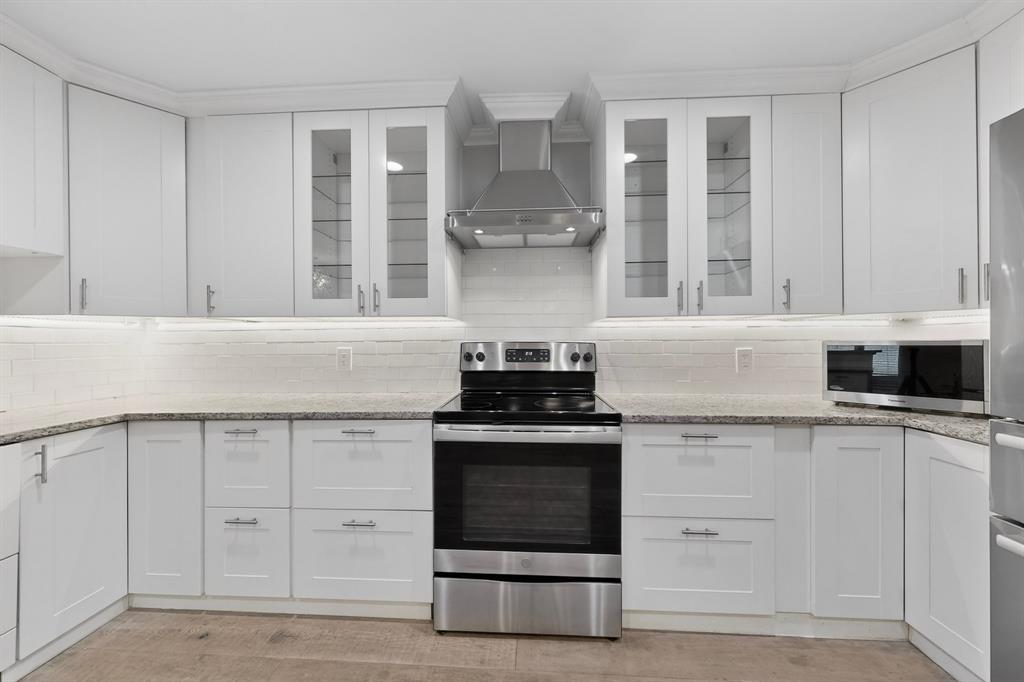 7631 Meadow Road Dallas, TX 75230 - Photo 13 of 40 A bright kitchen featuring white cabinets and sleek stainless steel appliances, creating a modern and clean look.