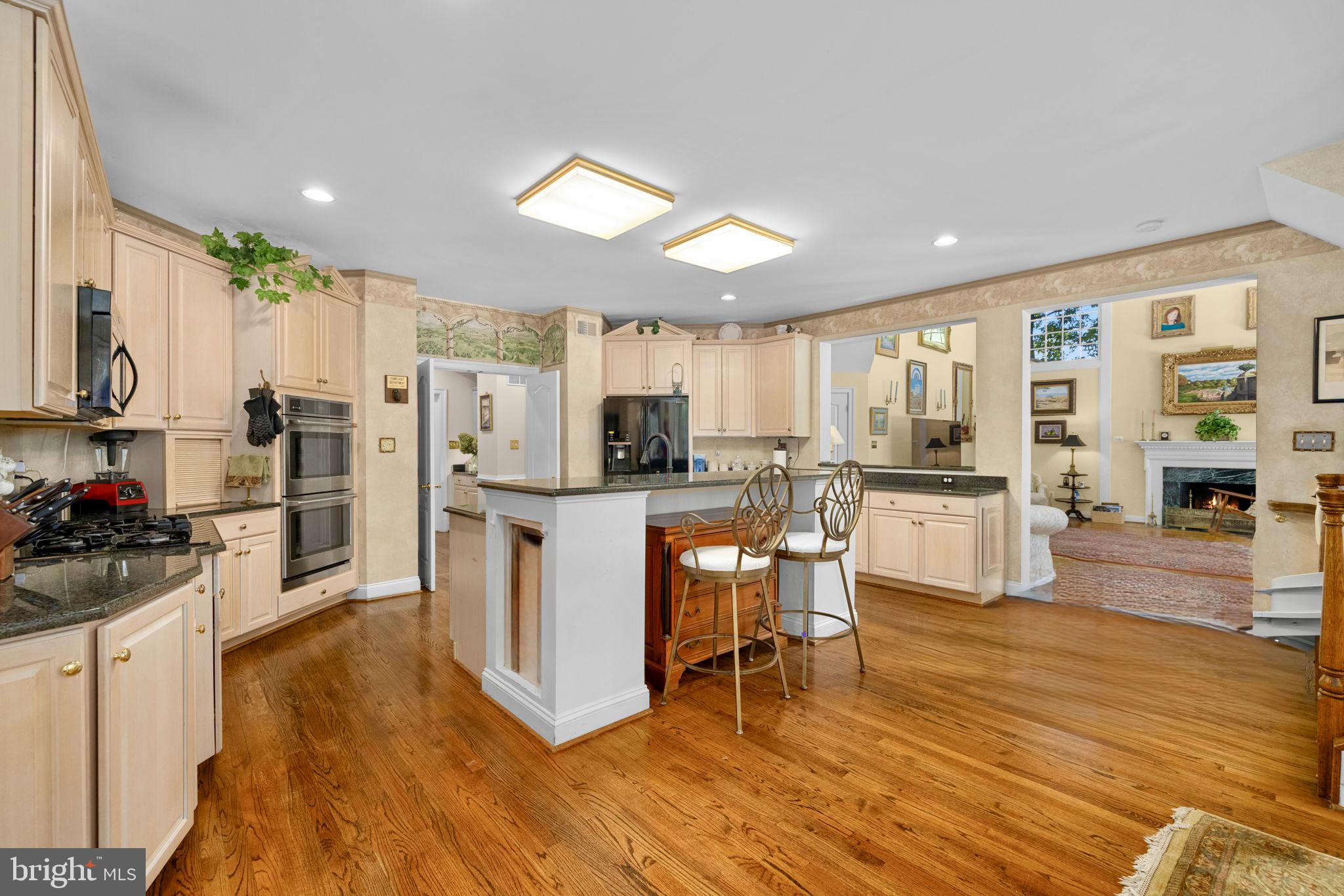 897 Chinquapin Road McLean, VA 22102 - Photo 26 of 66 a kitchen with stainless steel appliances kitchen island granite countertop a refrigerator a stove top oven a sink dishwasher and white cabinets with wooden floor