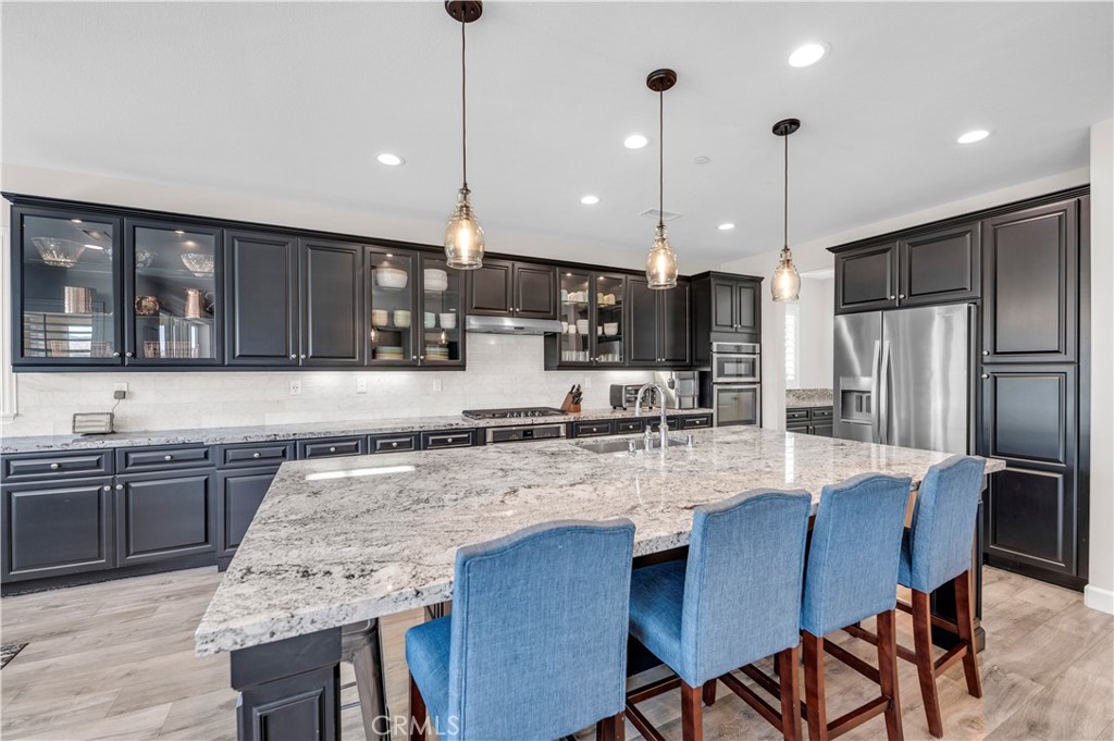 33303 Barmetta Lane Temecula, CA 92592 - Photo 19 of 46 a kitchen with granite countertop kitchen island stainless steel appliances a sink a stove a table and chairs