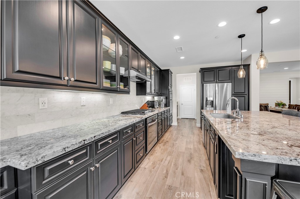 33303 Barmetta Lane Temecula, CA 92592 - Photo 20 of 46 a large kitchen with stainless steel appliances granite countertop plenty wooden cabinets counter space a sink and wooden floor