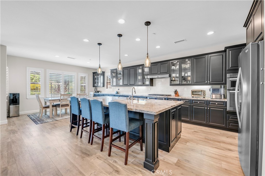 33303 Barmetta Lane Temecula, CA 92592 - Photo 21 of 46 a kitchen with stainless steel appliances granite countertop a table chairs and a refrigerator