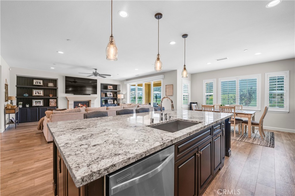 33303 Barmetta Lane Temecula, CA 92592 - Photo 22 of 46 a kitchen with granite countertop kitchen island stainless steel appliances a table chairs sink and wooden floor