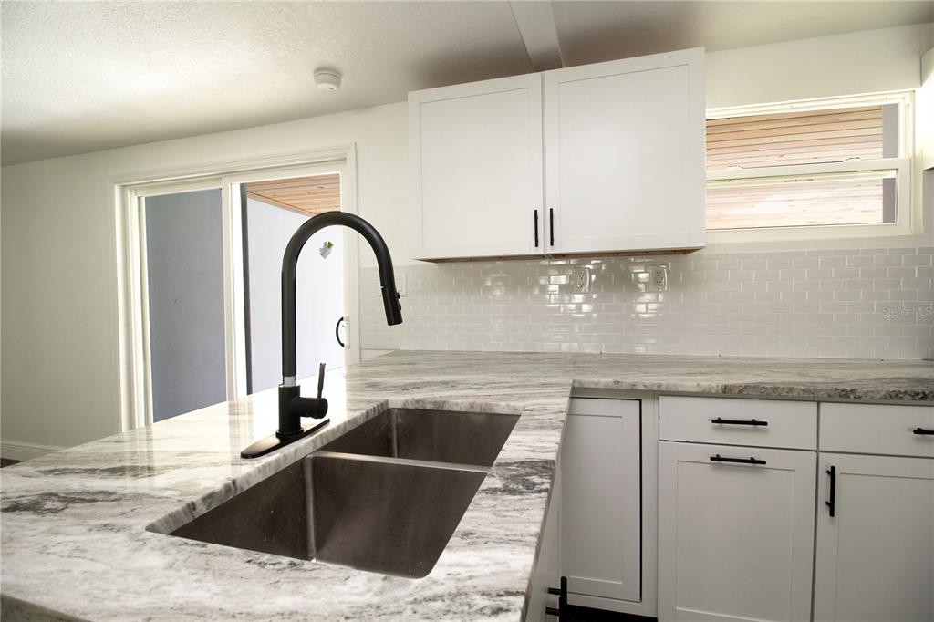 39912 Jerry Road Zephyrhills, FL 33540 - Photo 14 of 59 a kitchen with granite countertop a sink and white cabinets