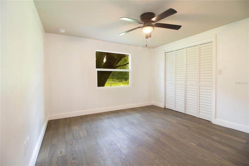 39912 Jerry Road Zephyrhills, FL 33540 - Photo 31 of 59 an empty room with wooden floor chandelier fan and windows