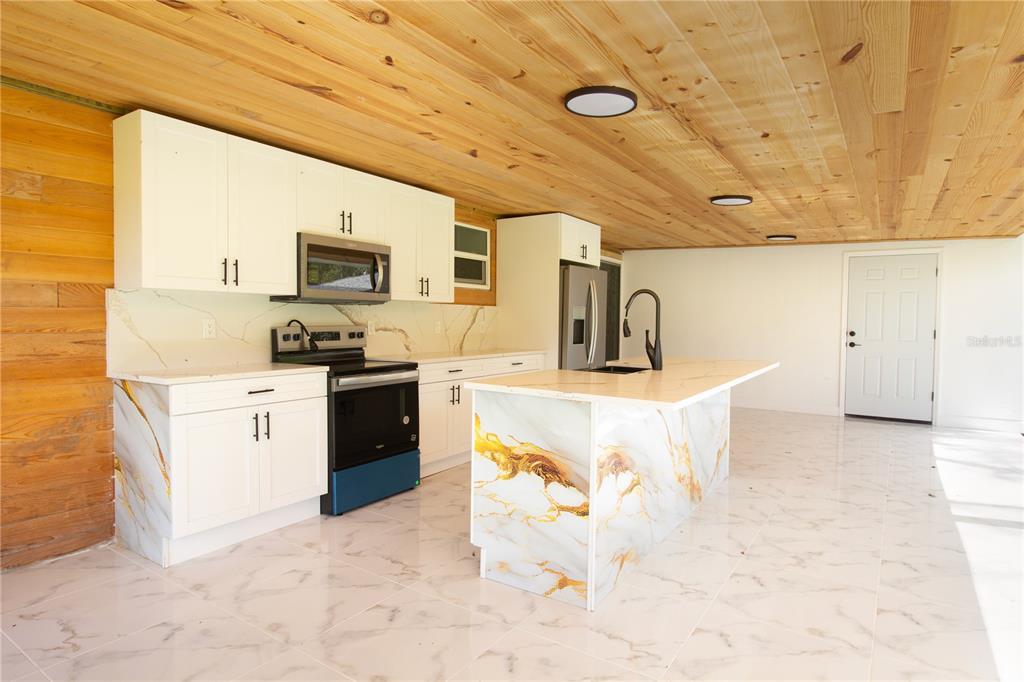 39912 Jerry Road Zephyrhills, FL 33540 - Photo 44 of 59 a kitchen with stainless steel appliances kitchen island granite countertop a sink and cabinets