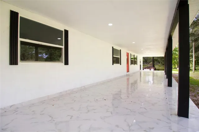 an empty room with windows and ceiling fan
