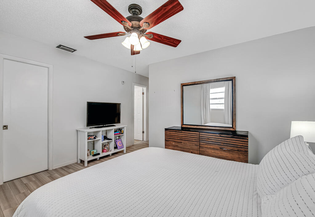 23428 Country Club Drive East Boca Raton, FL 33428 - Photo 19 of 32 a bedroom with a bed and a flat tv screen on dresser