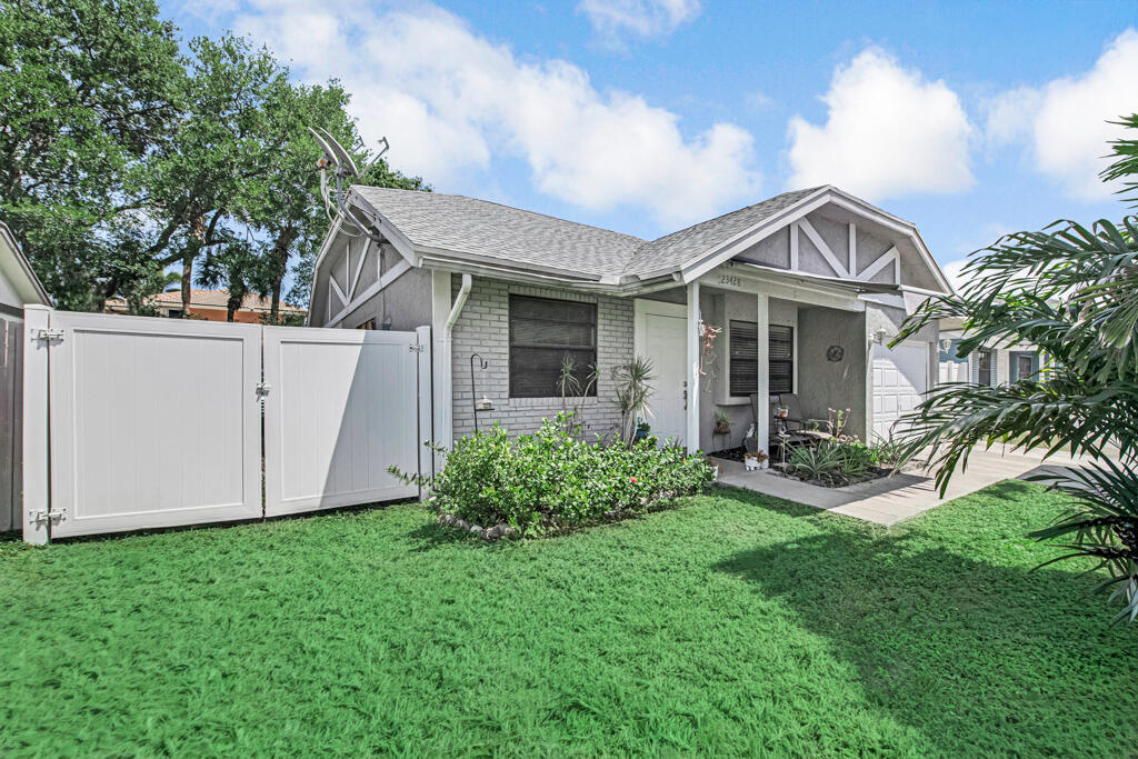 23428 Country Club Drive East Boca Raton, FL 33428 - Photo 4 of 32 a front view of a house with a garden and yard
