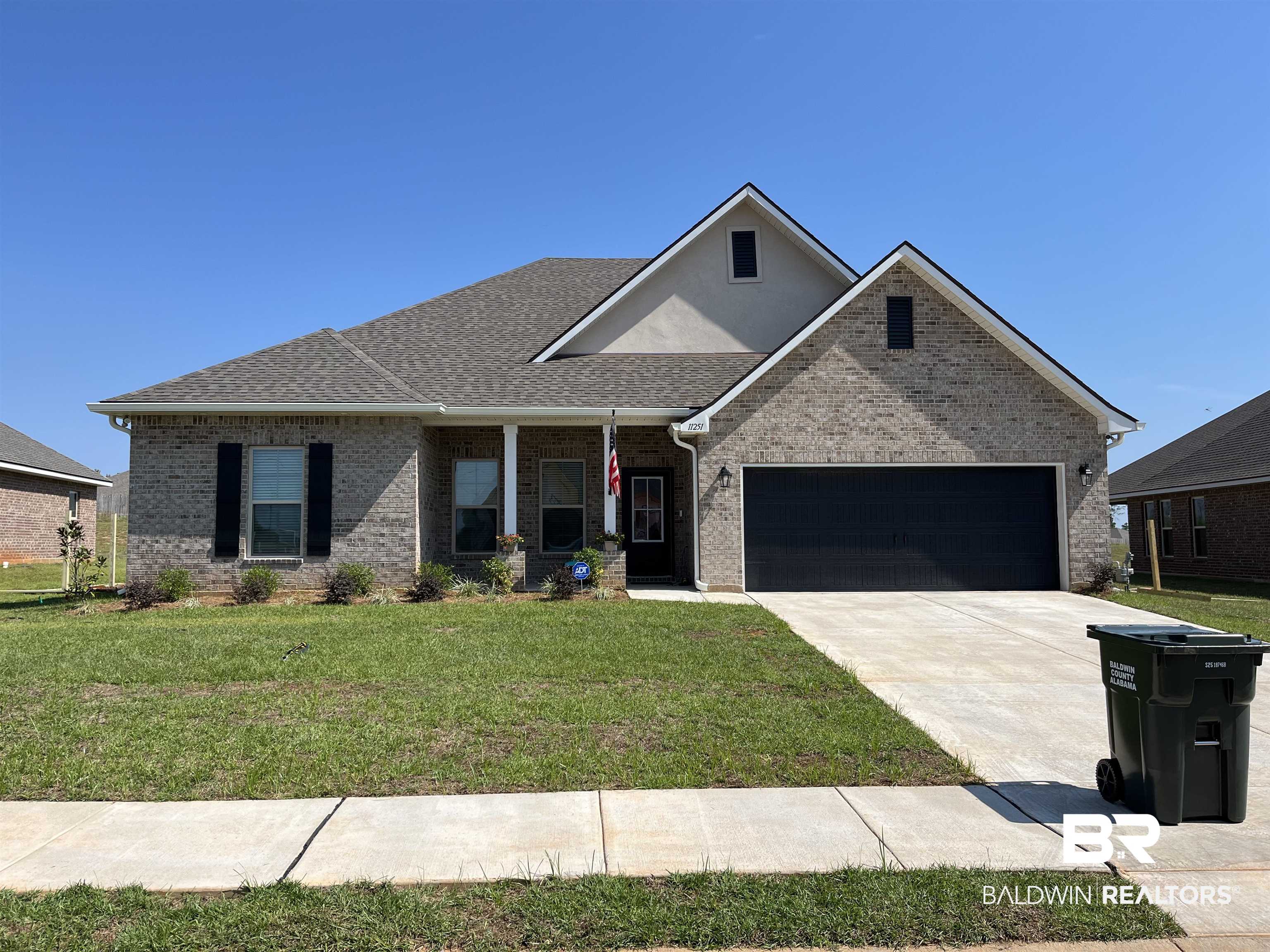 11251 Bonaventure Avenue Daphne, AL 36526 - Photo 1 of 3 View of front of house with a porch, brick siding, a front yard, driveway, and a garage