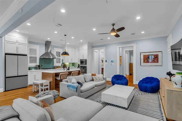 a living room with furniture a wooden floor and kitchen view