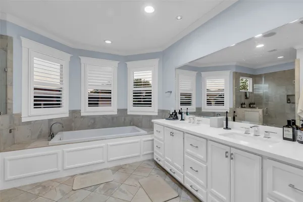 a spacious bathroom with double vanity a window a double vanity and a bathtub