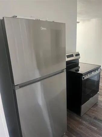 a close view of a refrigerator in kitchen and an empty room