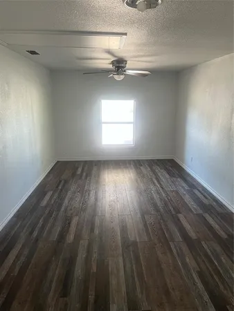 an empty room with wooden floor chandelier and windows