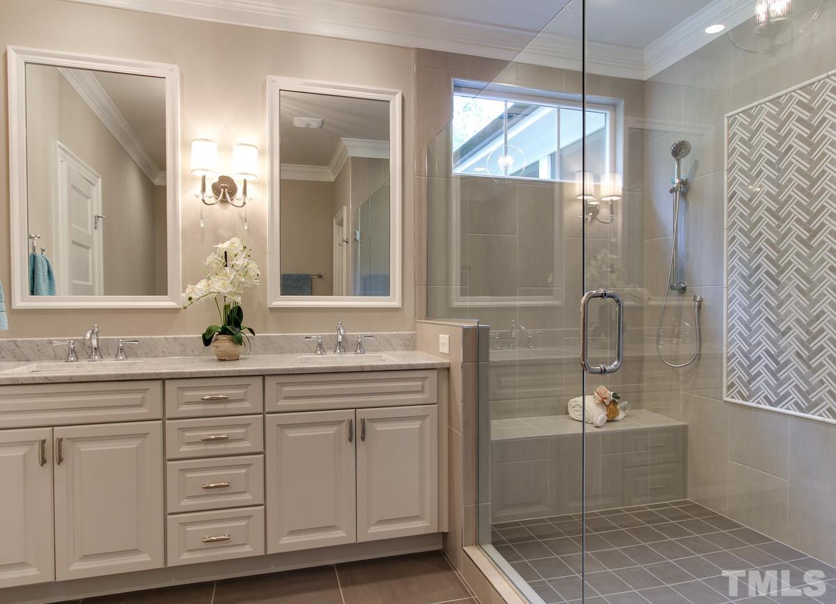 8808 Breeland Way Raleigh, NC 27613 - Photo 14 of 25 a bathroom with a double vanity sink a mirror a shower and a bathtub