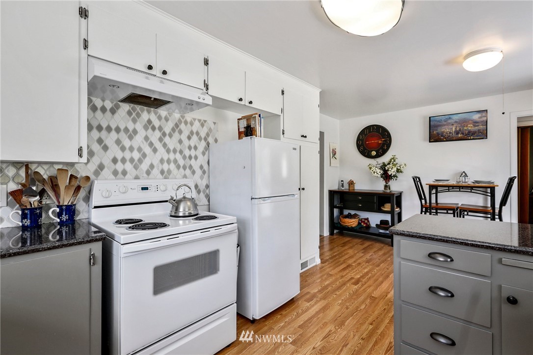 717 224th Street Southwest Bothell, WA 98021 - Photo 14 of 40 a kitchen with a refrigerator a stove top oven a clock and wooden floor