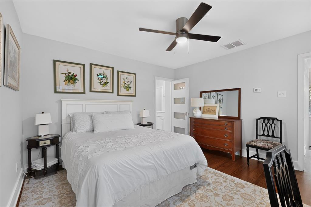 4548 Roland Avenue, Unit A Dallas, TX 75219 - Photo 18 of 31 White paneled headboard, ceiling fan with integrated lighting, wood-finish flooring, and light gray wall paint