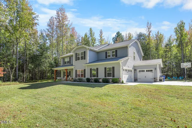 a front view of a house with a garden and trees