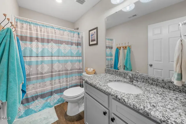 a bathroom with a granite countertop toilet sink and mirror
