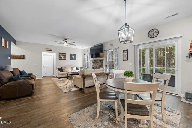 a view of a dining room and livingroom with furniture wooden floor a chandelier