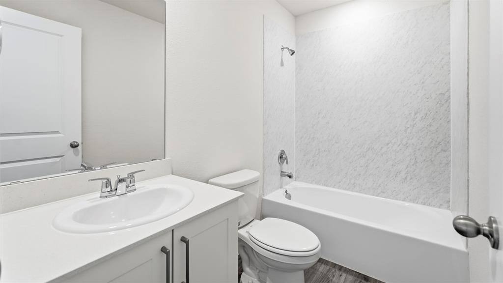 3519 Spring Time Street Forney, TX 75126 - Photo 4 of 37 Bathroom featuring a white vanity with an integrated sink, chrome faucet, and storage cabinetry with dark hardware