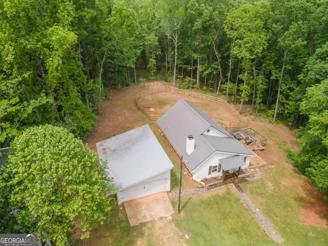 an aerial view of a house with a yard and a forest