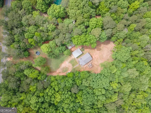 an aerial view of a house with outdoor space and trees all around