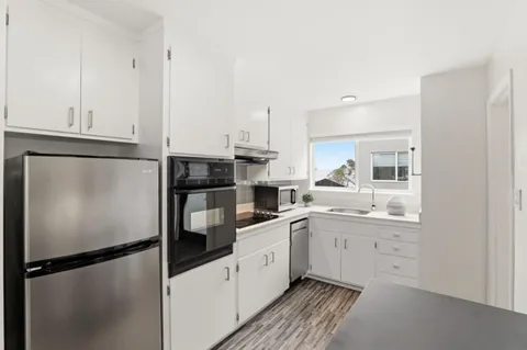 a kitchen with a refrigerator and white cabinets