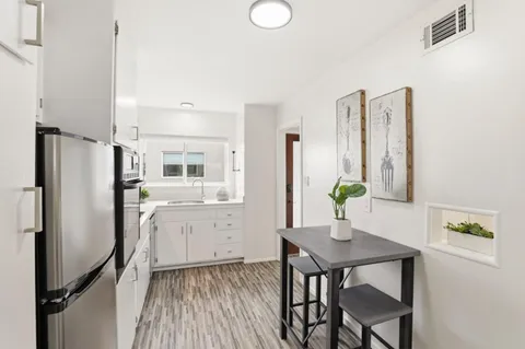 a kitchen with stainless steel appliances a refrigerator a table and chairs in it