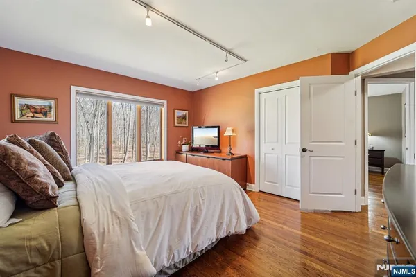 a spacious bedroom with a bed and wooden floor