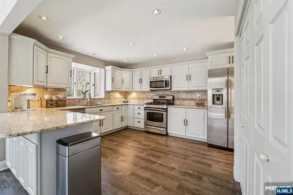a kitchen with granite countertop white cabinets and stainless steel appliances