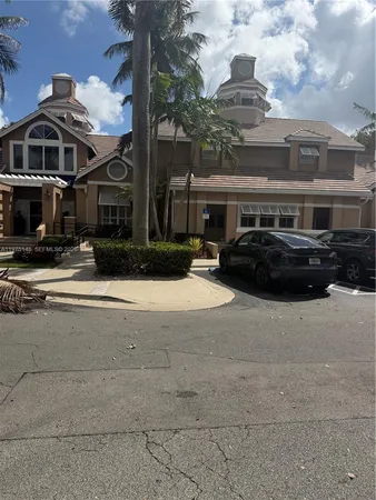 a front view of a building with streets and trees