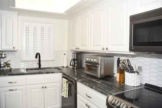 a kitchen with stainless steel appliances granite countertop a sink and a stove