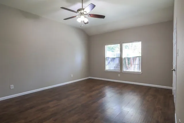 a view of empty room with wooden floor and fan