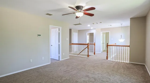 an empty room with ceiling fan and windows