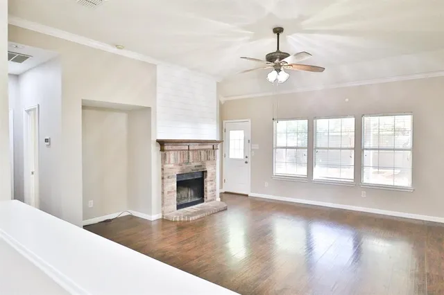 a view of an empty room with wooden floor fireplace and a window