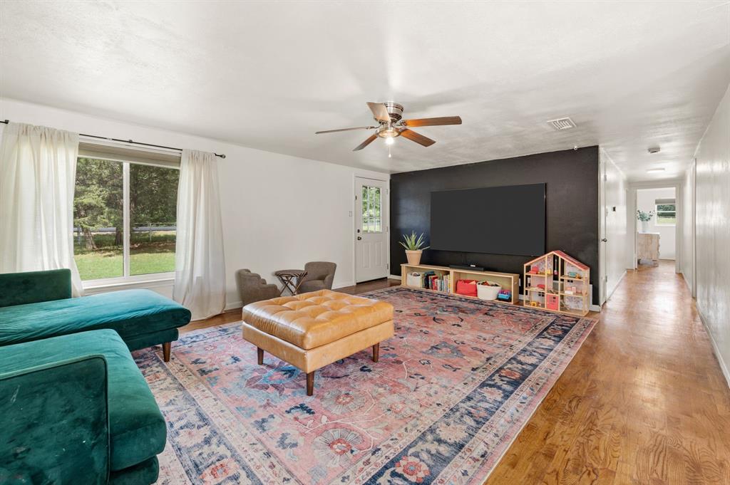3900 Moseley Road Cross Roads, TX 76227 - Photo 3 of 36 Living area featuring wood-finish flooring, a ceiling fan, and a large window providing natural light