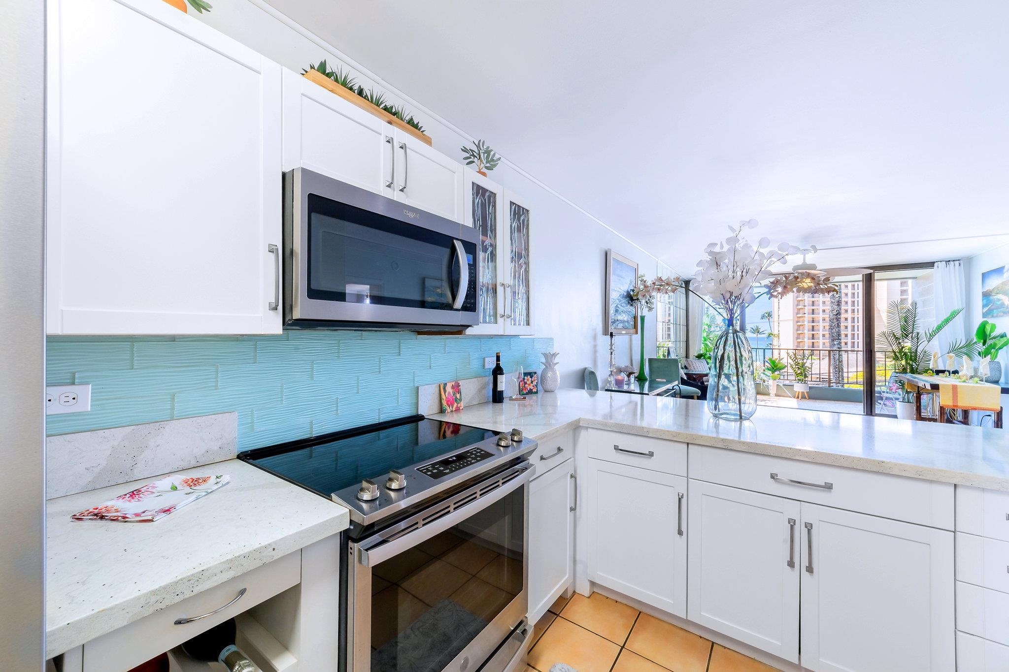 4310 Lower Honoapiilani Road, Unit 302 Lahaina, HI 96761 - Photo 11 of 50 a kitchen with stainless steel appliances white cabinets and a stove top oven