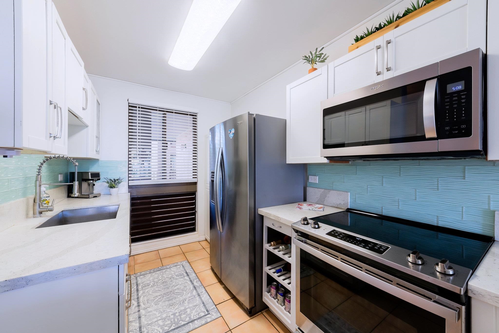 4310 Lower Honoapiilani Road, Unit 302 Lahaina, HI 96761 - Photo 14 of 50 a kitchen with stainless steel appliances a stove a microwave and cabinets
