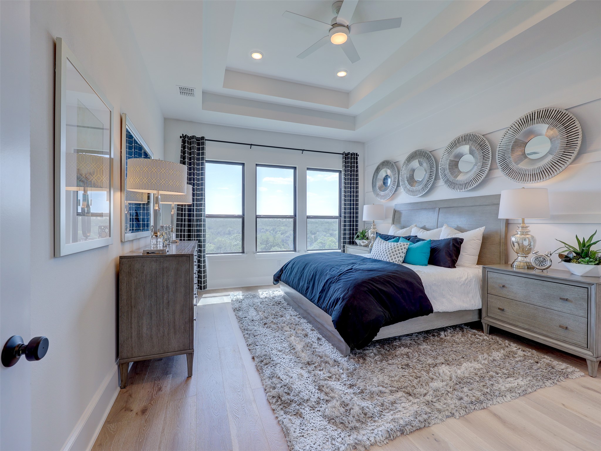 6220 Bower Well Road Austin, TX 78738 - Photo 11 of 28 Well-lit primary bedroom featuring a sophisticated tray ceiling and light wood flooring.
