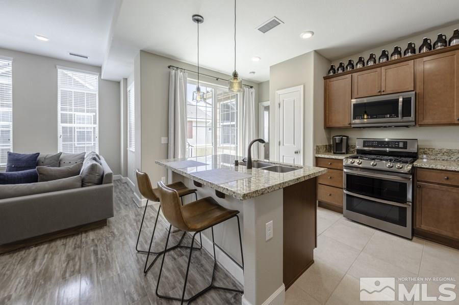 2029 Wind Ranch Road, Unit A Reno, NV 89521 - Photo 7 of 26 a kitchen with stainless steel appliances granite countertop a stove top oven a sink dishwasher a dining table and chairs with wooden floor