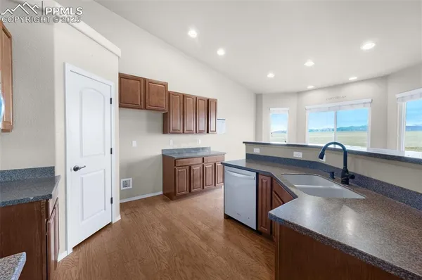 a large kitchen with stainless steel appliances granite countertop a sink dishwasher a stove and a refrigerator