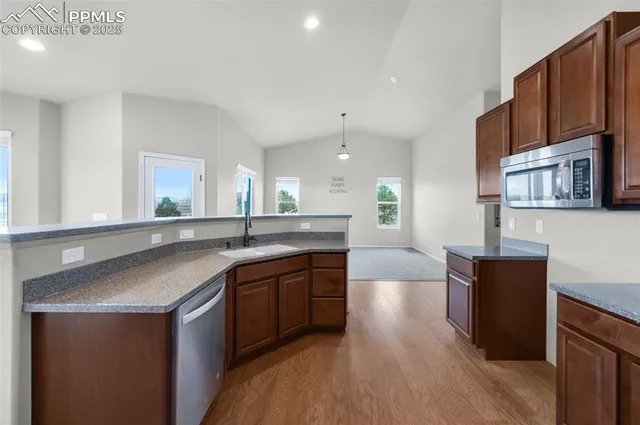 a kitchen with granite countertop kitchen island stainless steel appliances a stove a sink a refrigerator and a counter top space