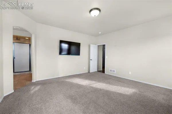 an empty room with a flat screen tv and windows