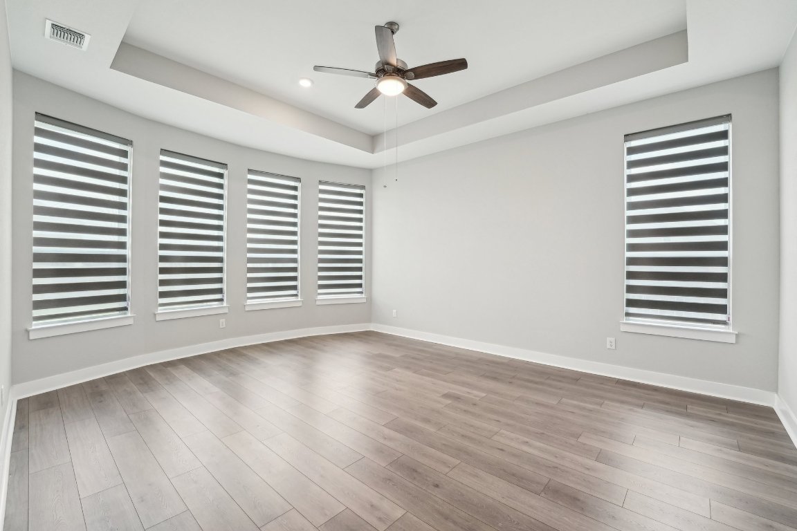 4216 Caroline Mae Cove Pflugerville, TX 78660 - Photo 20 of 32 an empty room with wooden floor chandelier fan and windows