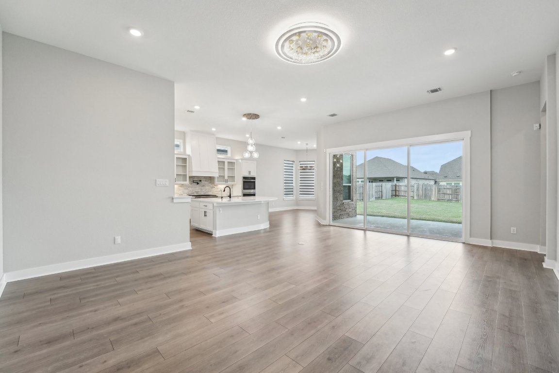 4216 Caroline Mae Cove Pflugerville, TX 78660 - Photo 6 of 32 a view of an empty room with wooden floor and a window
