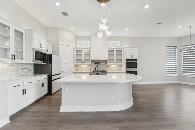 a kitchen with stainless steel appliances granite countertop a sink a stove a refrigerator and island with wooden floor